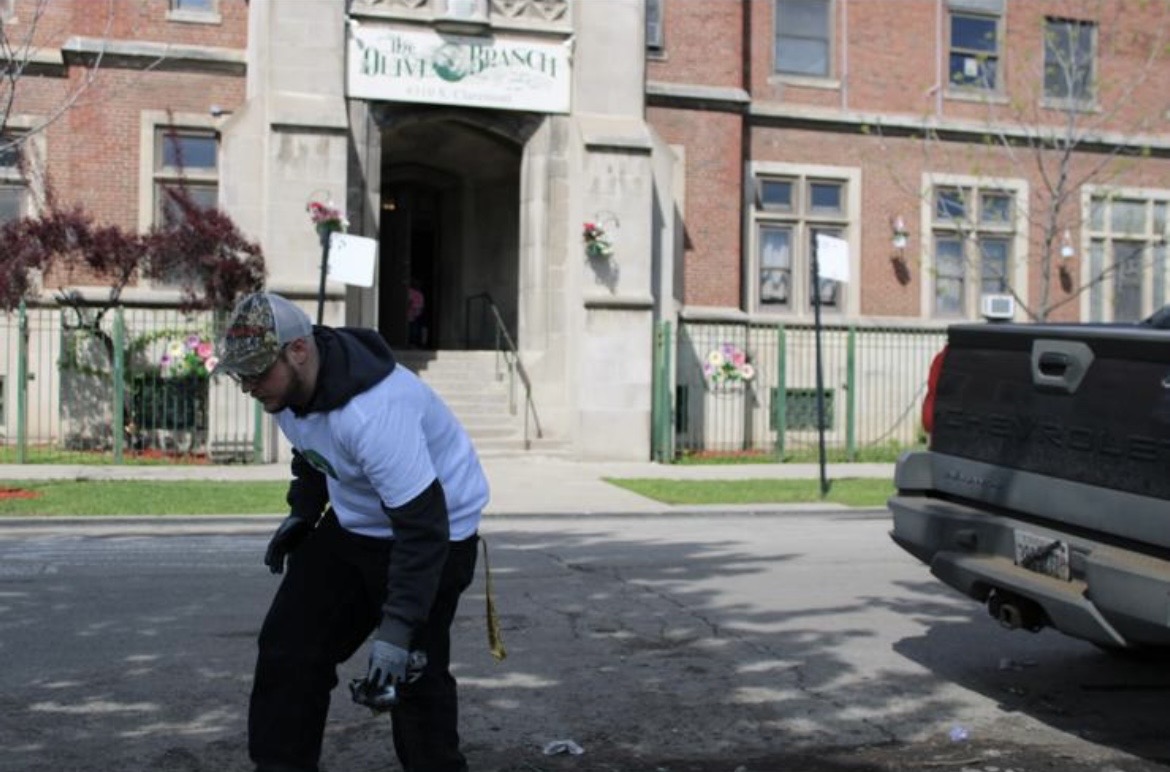 Volunteer cleaning the street outside The Olive Branch