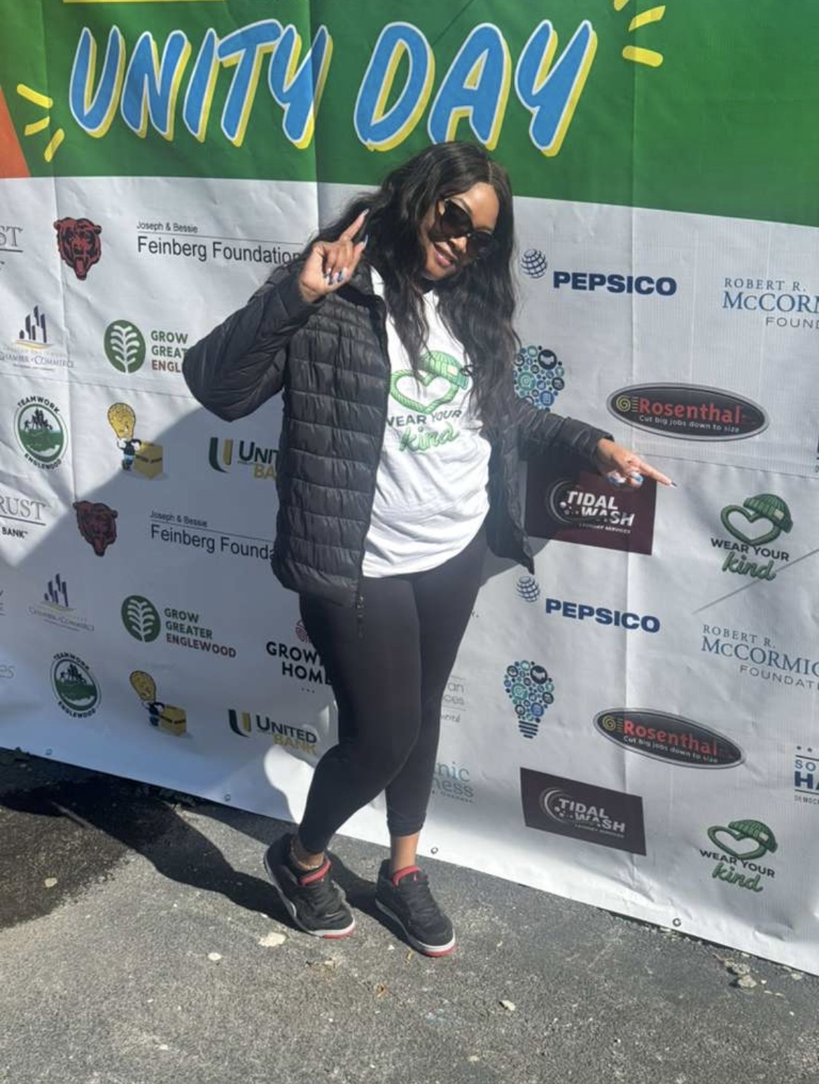 Volunteer posing at the Unity Day sponsor wall